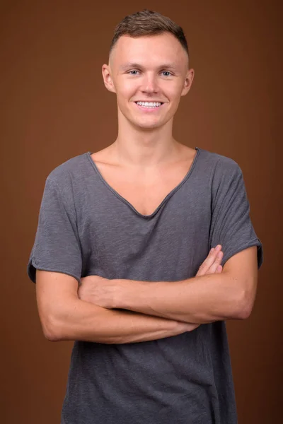 Hombre joven con camisa gris sobre fondo marrón — Foto de Stock