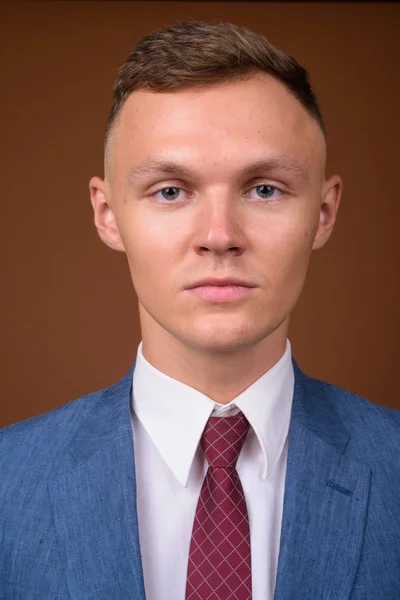 Fiatal üzletember visel öltönyt, barna háttér — Stock Fotó