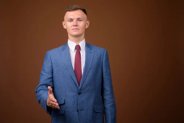 茶色の背景に対してスーツを着て青年実業家 — ストック写真