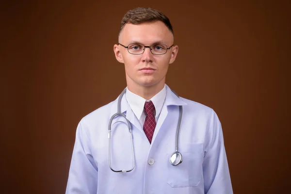 Νεαρός γιατρός φοράει γυαλιά καφέ φόντο — Φωτογραφία Αρχείου