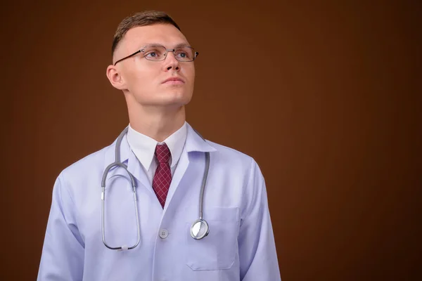 Jeune homme médecin portant des lunettes sur fond brun — Photo