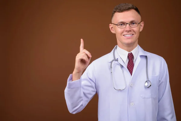 Jeune homme médecin portant des lunettes sur fond brun — Photo