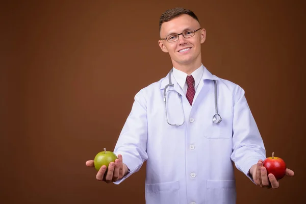 Молодой врач в очках на коричневом фоне — стоковое фото