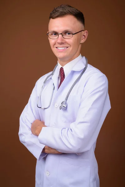Jeune homme médecin portant des lunettes sur fond brun — Photo