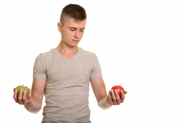 Joven hombre caucásico elegir entre manzana roja y verde — Foto de Stock