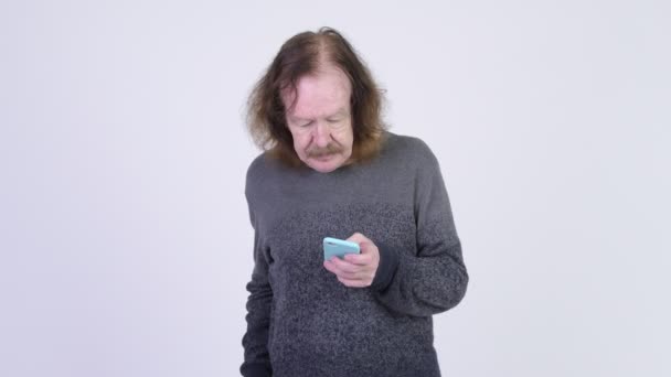 Щасливий старший чоловік з вусами використовує телефон і отримує хороші новини — стокове відео