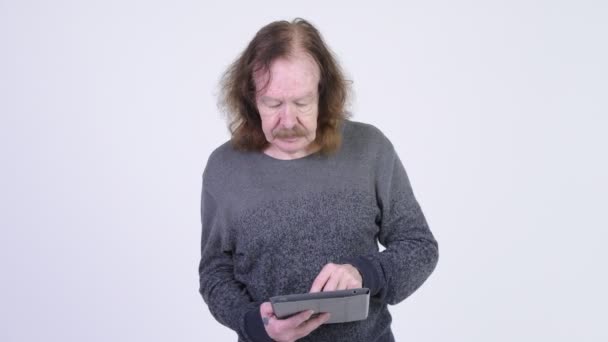 Homem sênior feliz com bigode pensando ao usar tablet digital — Vídeo de Stock