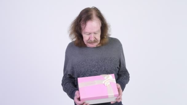 Glücklicher älterer Mann lächelt, während er eine Geschenkbox in der Hand hält — Stockvideo