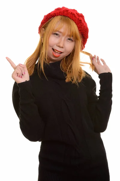 Joven feliz mujer asiática sonriendo y señalando con el dedo hacia arriba mientras pla —  Fotos de Stock