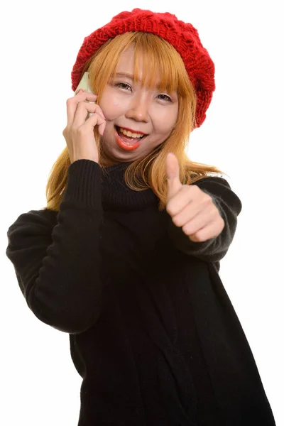 Young happy Asian woman smiling while talking on mobile phone an — Stock Photo, Image