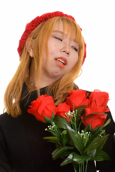 Fiatal, szomorú ázsiai nő vörös rózsákkal a kezében és félrenéz. — Stock Fotó
