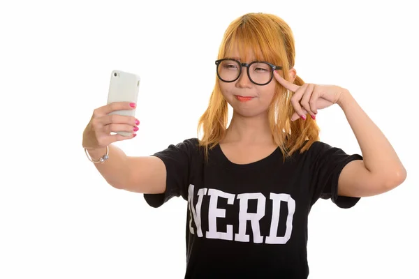 携帯電話で selfie を取る若いかわいいアジアのオタク女と — ストック写真