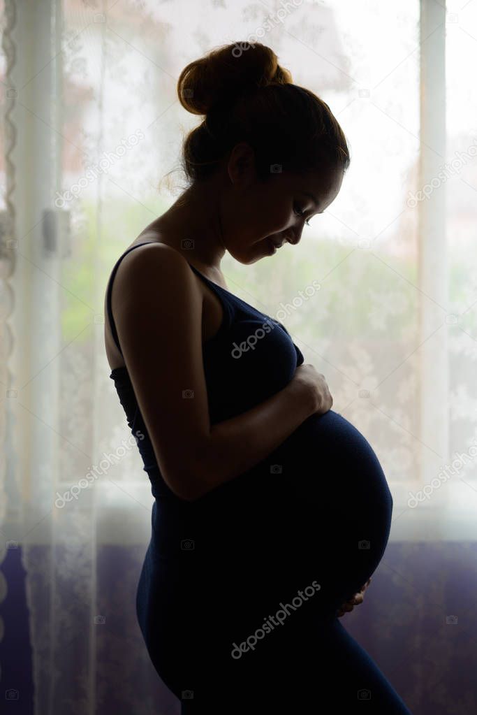 Mother loving her baby in silhouette by the window