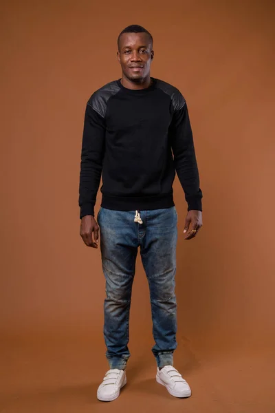 Studio shot of young African man against brown background