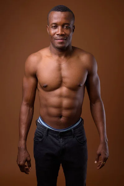Молодой африканский мужчина без рубашки на коричневом фоне — стоковое фото
