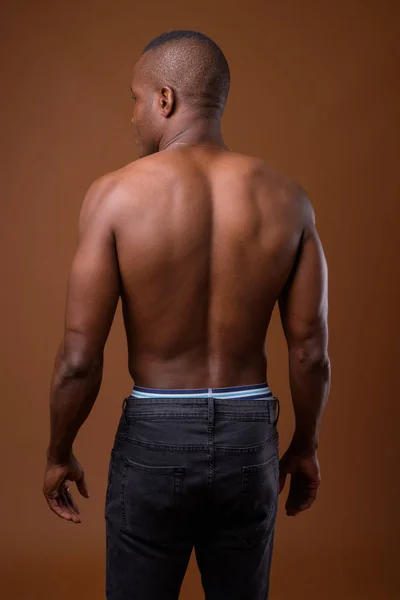 Молодой африканский мужчина без рубашки на коричневом фоне — стоковое фото