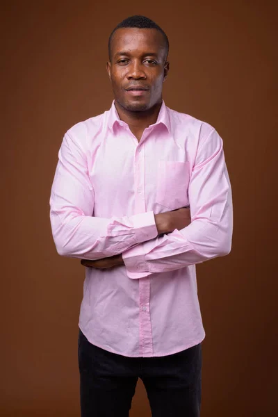 Estudio de un joven empresario africano contra fondo marrón —  Fotos de Stock