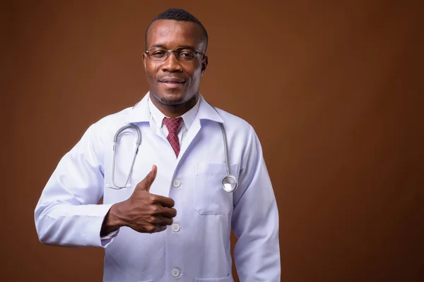Студийный снимок молодого африканского врача на коричневом фоне — стоковое фото