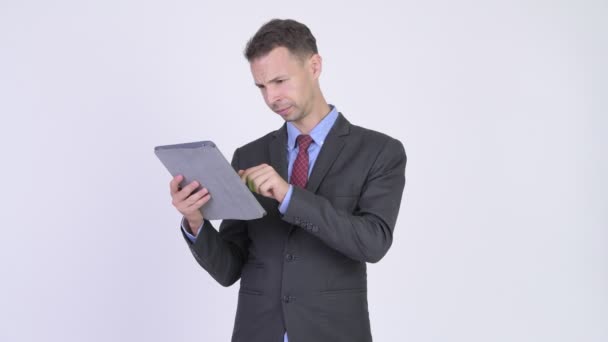 Estúdio tiro de homem de negócios usando tablet digital e olhando chocado — Vídeo de Stock