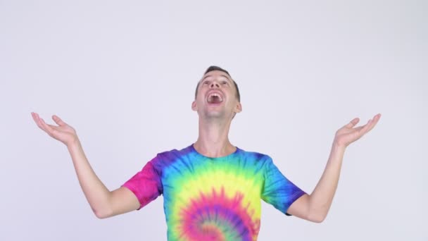 Studio shot of happy man with tie-dye shirt catching something — Stock Video