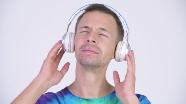 Estudio de tiro de hombre feliz con camisa tie-dye y escuchar música — Vídeos de Stock