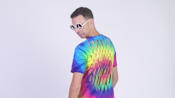 Rear view of hippie man wearing sunglasses with peace sign and looking back — Stock Video