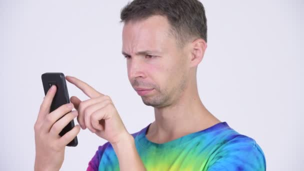 Strzał studio szczęśliwy człowiek z tie-dye shirt przy użyciu telefonu — Wideo stockowe
