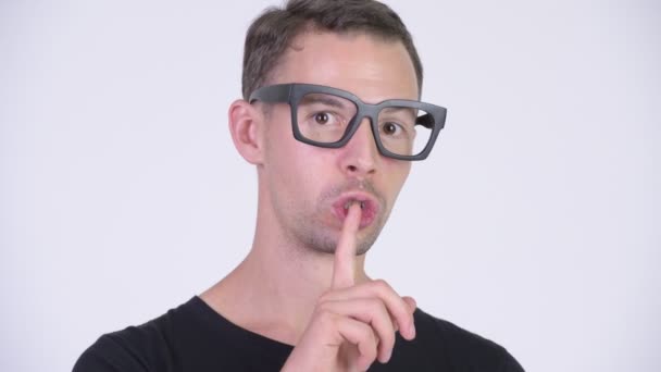 Estudio de tiro de hombre nerd feliz con el dedo en los labios — Vídeo de stock