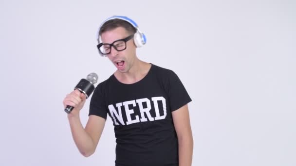 Studio shot of nerd man sing with microphone and headphones — Stock Video