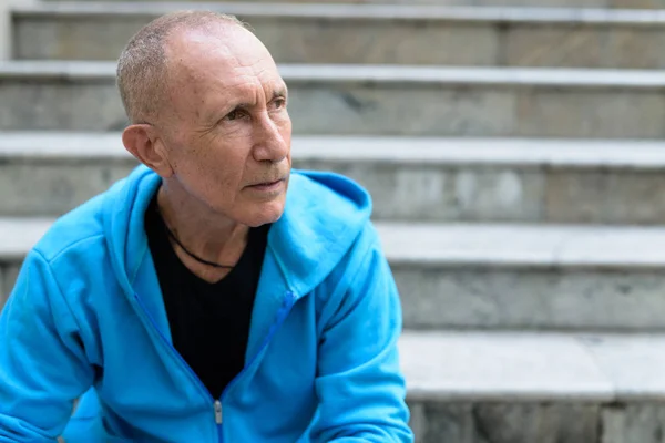 Närbild på skallig senior man tänker medan du sitter på stairc — Stockfoto