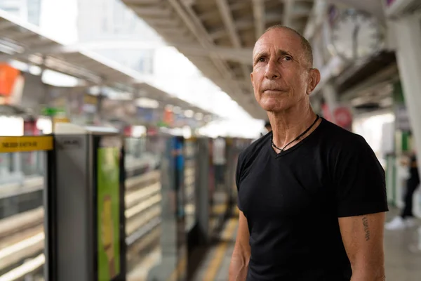 Bald senior tourist man waiting for the train at BTS sky train s — Stock Photo, Image