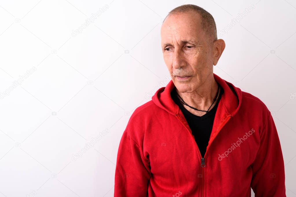 Close up of bald senior man thinking while looking sad against w