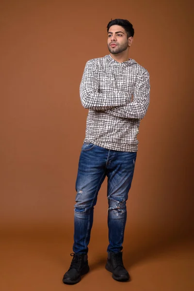 Young handsome Indian man against brown background