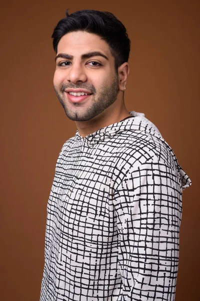 Young handsome Indian man against brown background