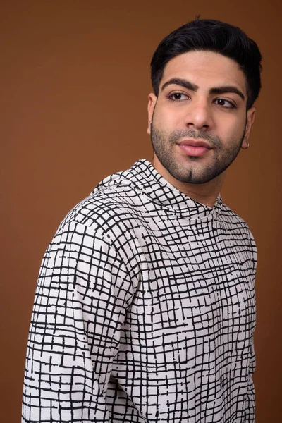 Young handsome Indian man against brown background