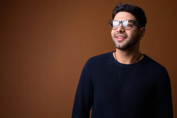 Joven hombre indio guapo sobre fondo marrón — Foto de Stock