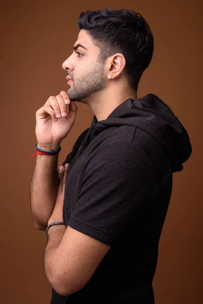 Young handsome Indian man against brown background