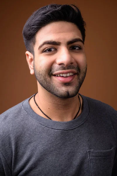 Junger hübscher indischer Mann mit braunem Hintergrund — Stockfoto