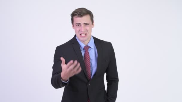 Молодой сердитый бизнесмен разговаривает с камерой — стоковое видео