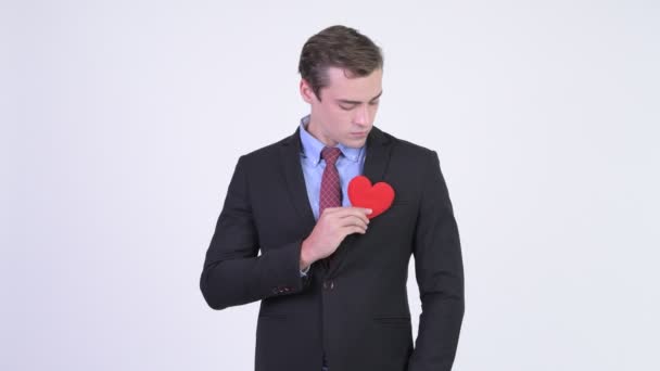 Joven feliz hombre de negocios guapo dando corazón rojo — Vídeo de stock