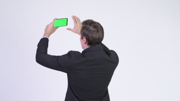 Vista trasera del joven hombre de negocios tomando fotos con el teléfono — Vídeos de Stock