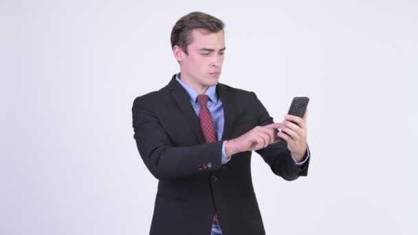 Young handsome businessman using phone and looking shocked — Stock Video