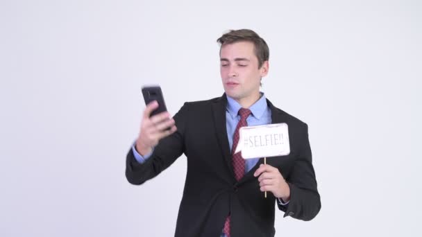 Joven feliz hombre de negocios guapo tomando selfie con el signo de papel — Vídeos de Stock