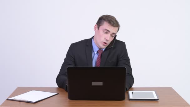 Young stressed businessman looking busy at work against wooden table — Stock Video