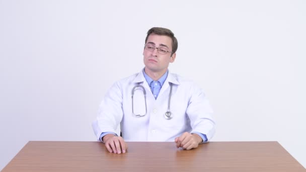 Mladý pohledný muž lékař rozhodování proti dřevěný stůl — Stock video