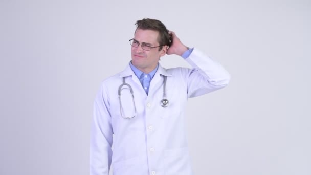 Молодий збентежений чоловік лікар подряпає голову — стокове відео