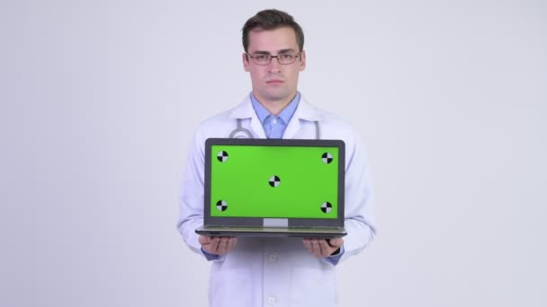 Ευτυχισμένος όμορφος νεαρός γιατρός δείχνει φορητό υπολογιστή — Αρχείο Βίντεο