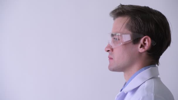 Профільний вигляд молодого красивого чоловіка лікаря, який думає під час носіння захисних окулярів — стокове відео