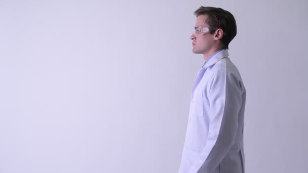 Вид профілю молодого щасливого красивого чоловіка лікаря в захисних окулярах з схрещеними руками — стокове відео