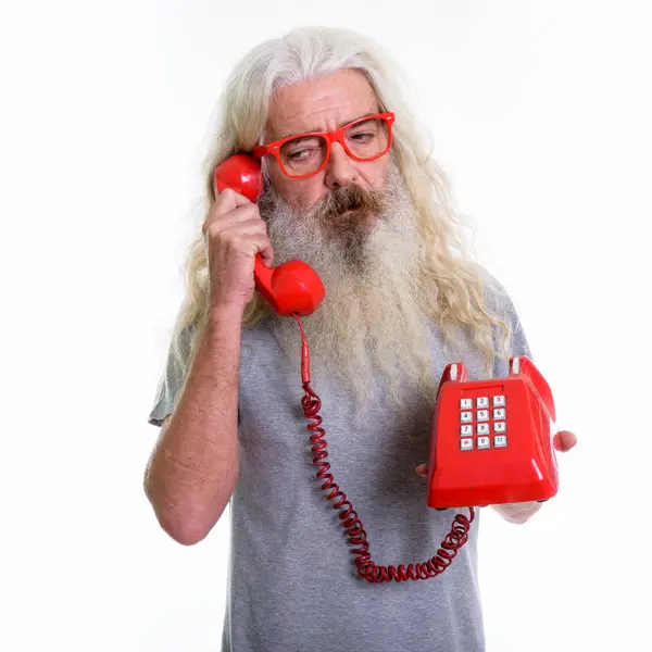 Studio shot van senior bebaarde man op zoek moe tijdens het gesprek op — Stockfoto